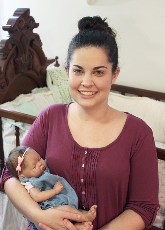 Emily Jameson holding a doll and smiling at camera